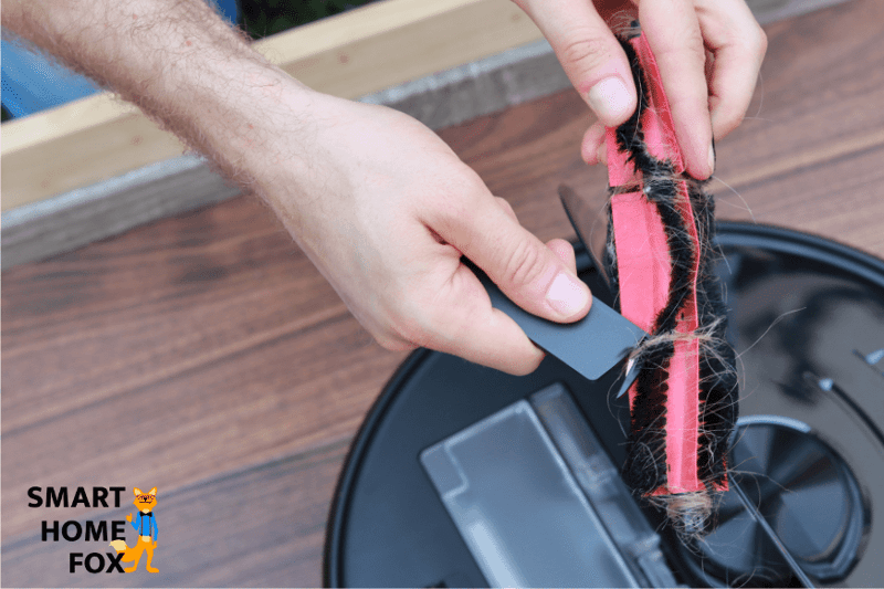 Removing hair from the Roborock S6 MaxV’s main brush with the supplied cleaning tool.